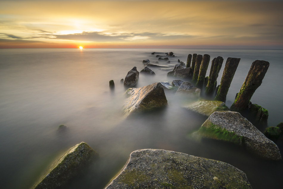Sunset over the sea blurred long shutter speed breakwaters