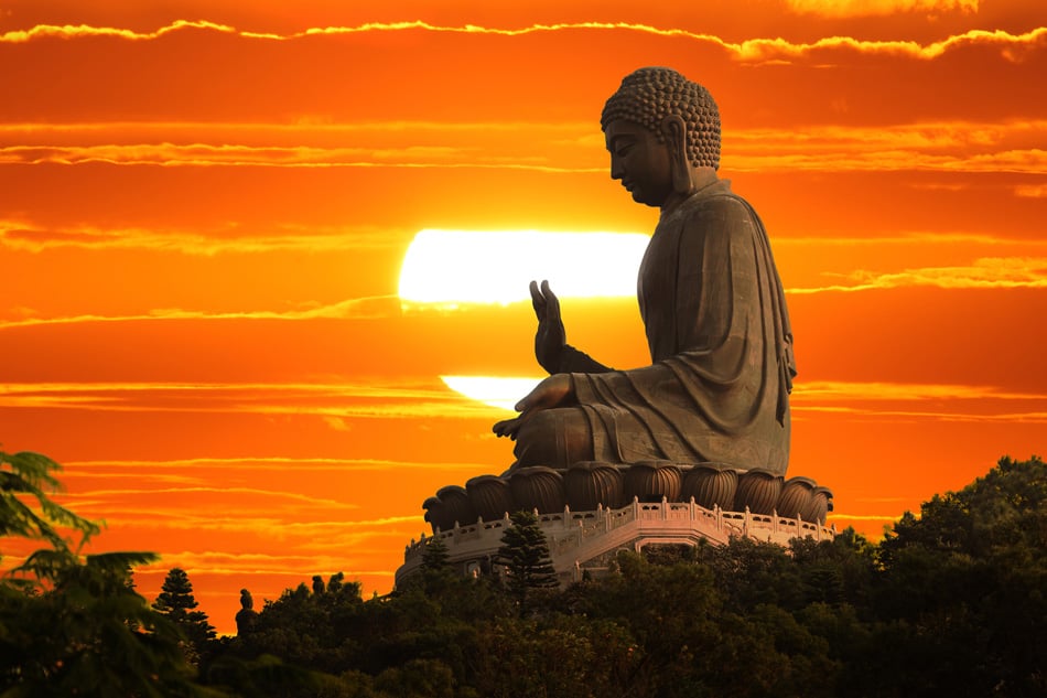 Buddha statue over scenic sunset sky background