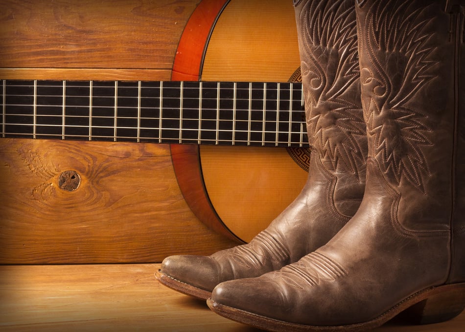 American Country music with guitar and cowboy shoes on wood