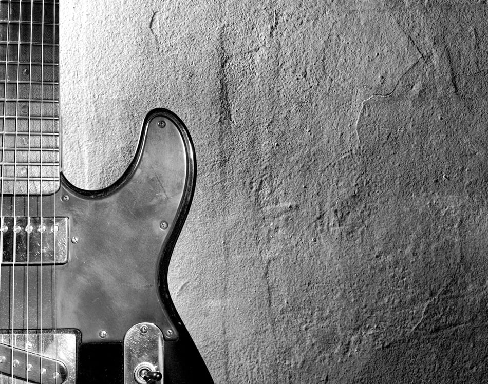 Black and white photo of an elertric guitar near wall