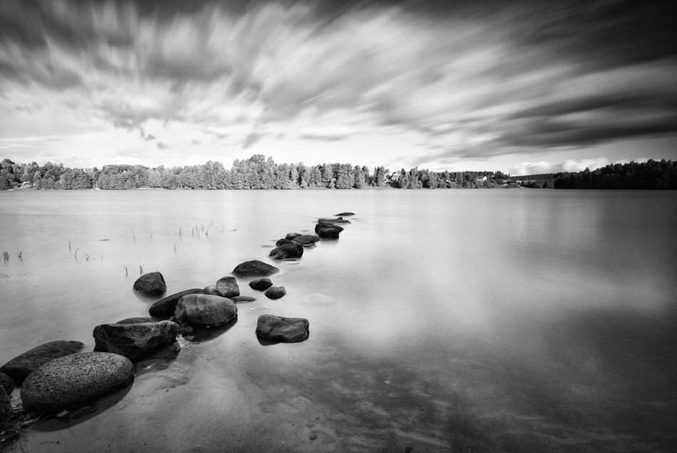 Moving clouds above a tranquil lake in black and white