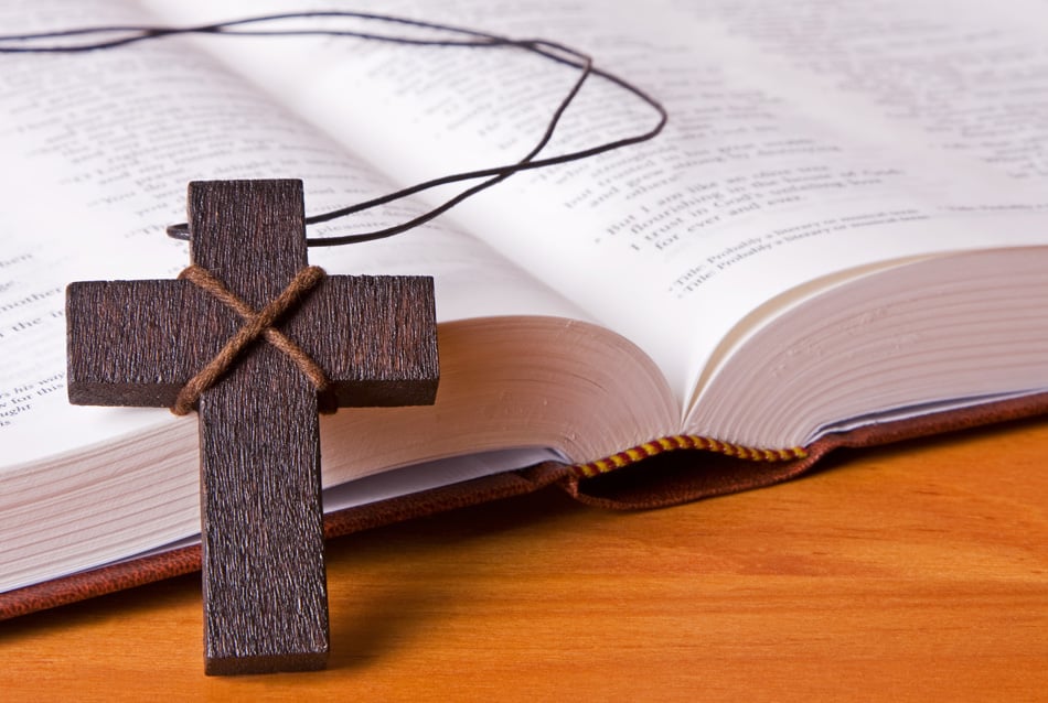 A Wooden Cross Resting Against The Holy Bible