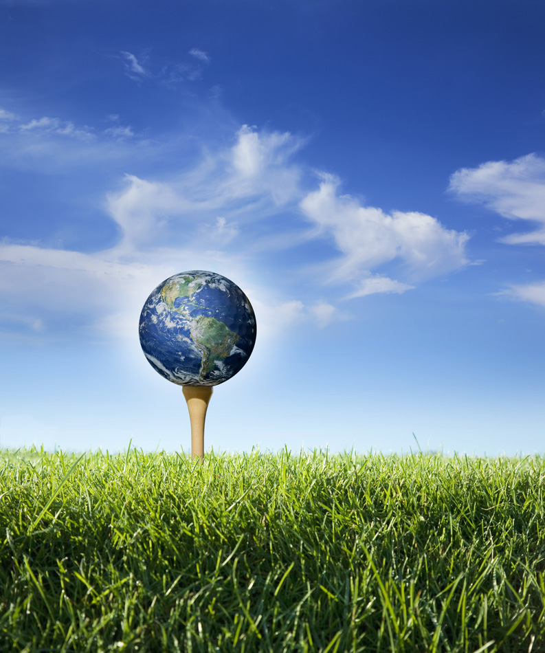 The Earth On A Golf Tee In Grass With Blue Sky And Clouds