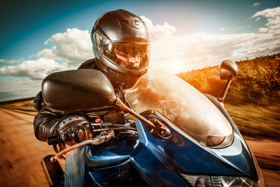 Biker In Helmet And Leather Jacket Racing On The Road
